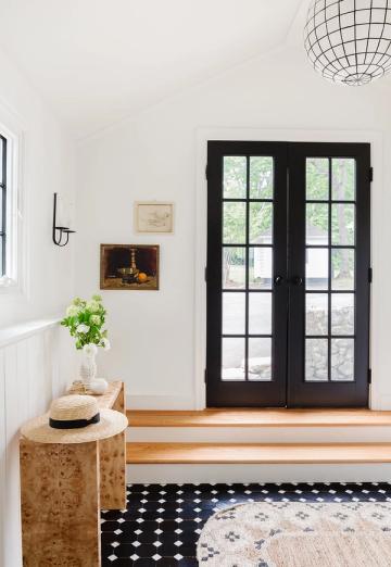Modern entryway with black French doors, geometric pendant, and monochrome pattern rug