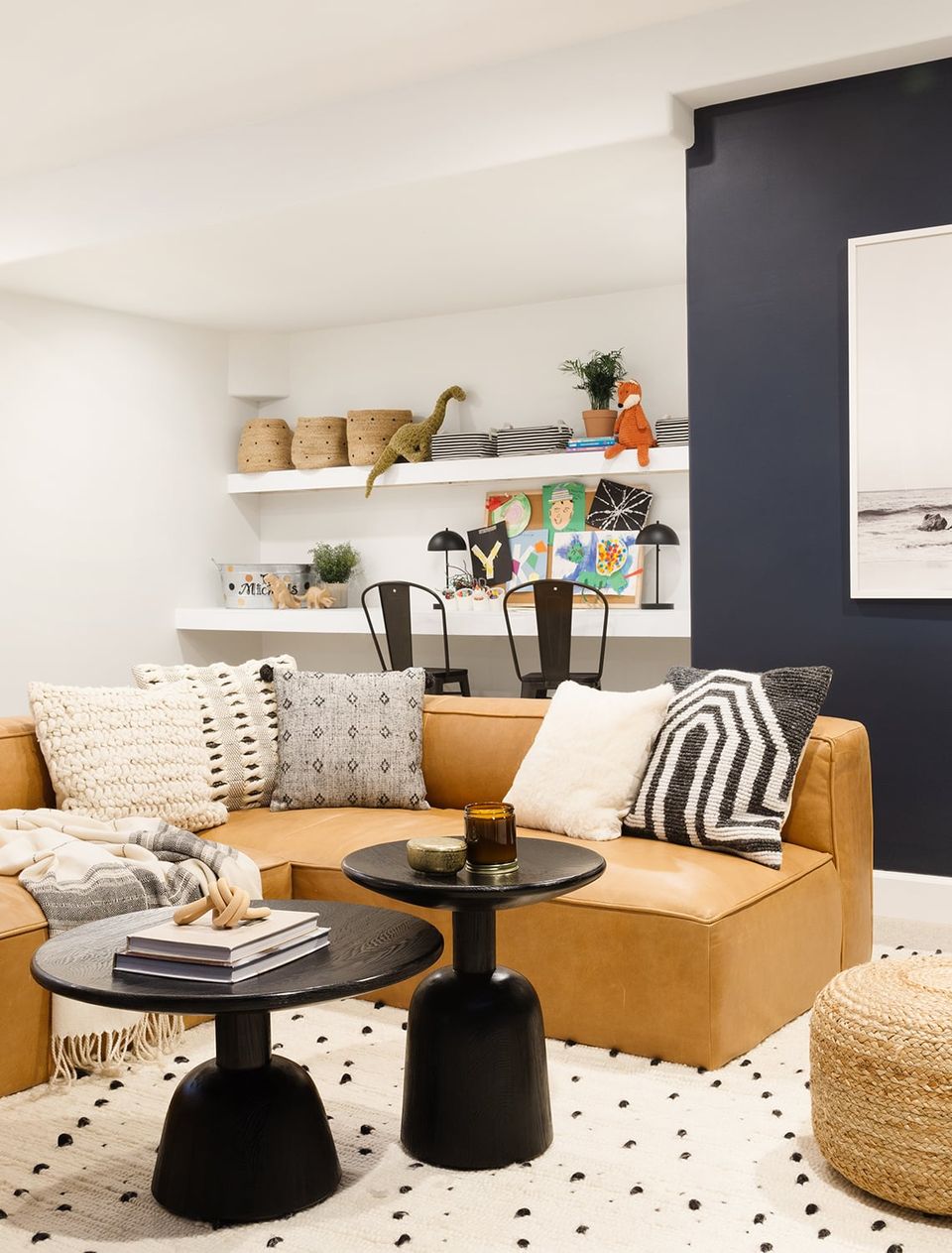 Contemporary lounge with caramel leather sofa, navy accent wall, and geometric patterned pillows for dynamic contrast
