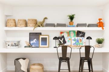 Modern homework station with floating shelves, natural wood storage baskets, black metal chairs, and pops of orange and teal accents