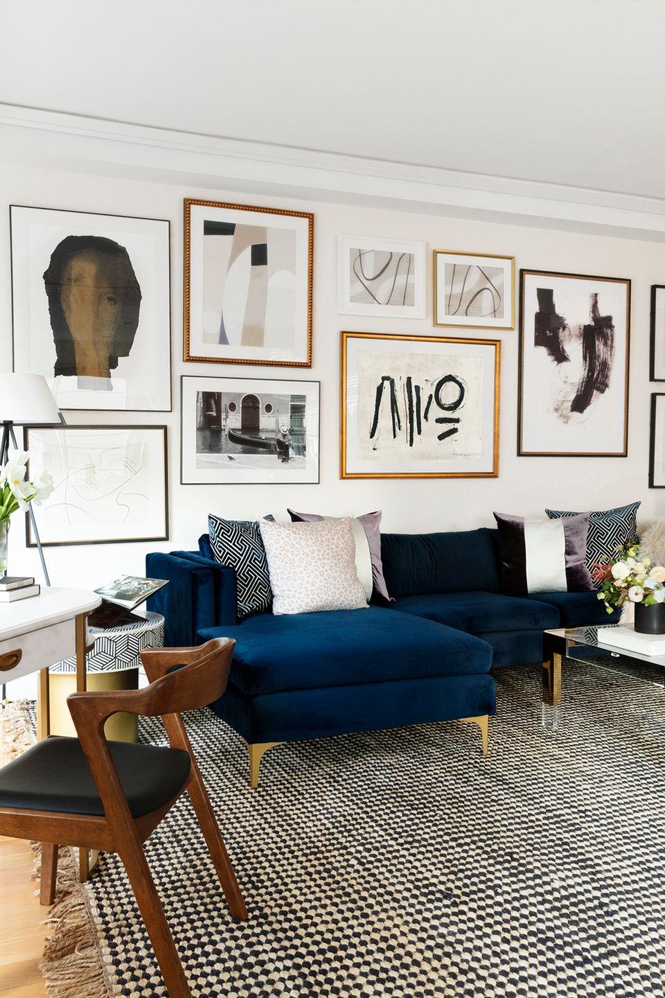 Modern gallery wall in neutral tones with navy sofa, mixed frame styles, geometric rug