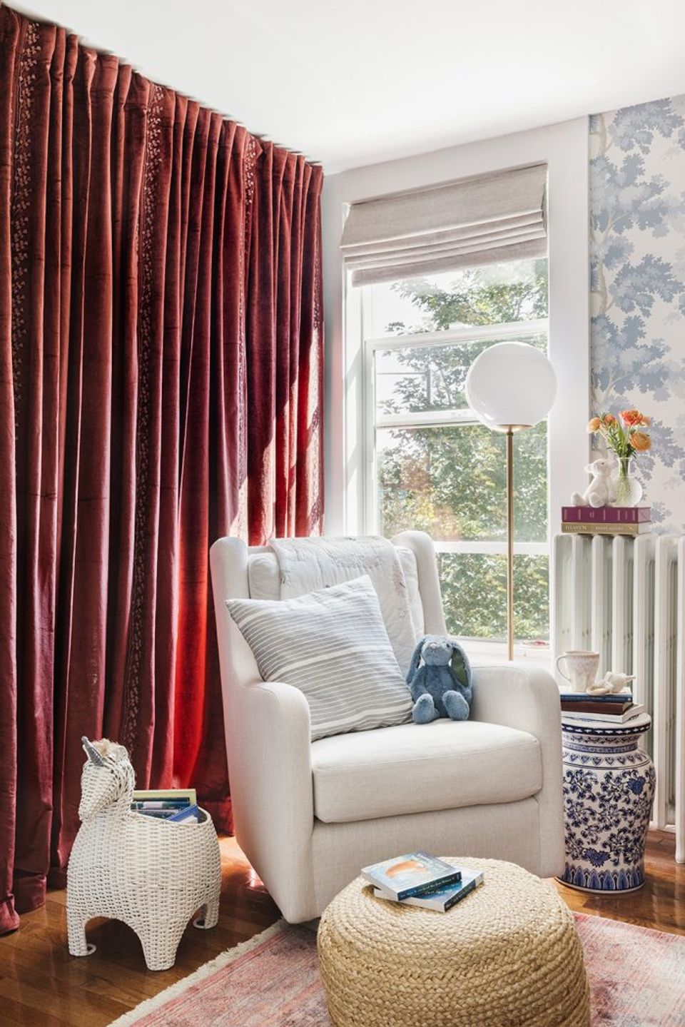 Eclectic reading nook with rich burgundy curtains, cream armchair, natural textures, and blue accents
