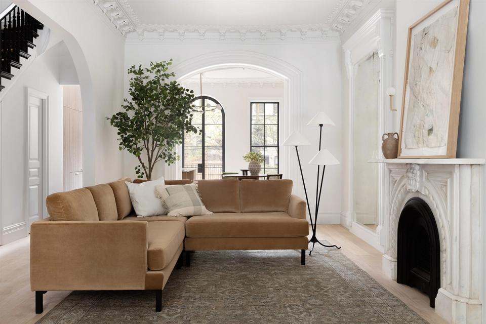 Serene neutral sanctuary with caramel sectional, curved archways, and minimalist modern fireplace