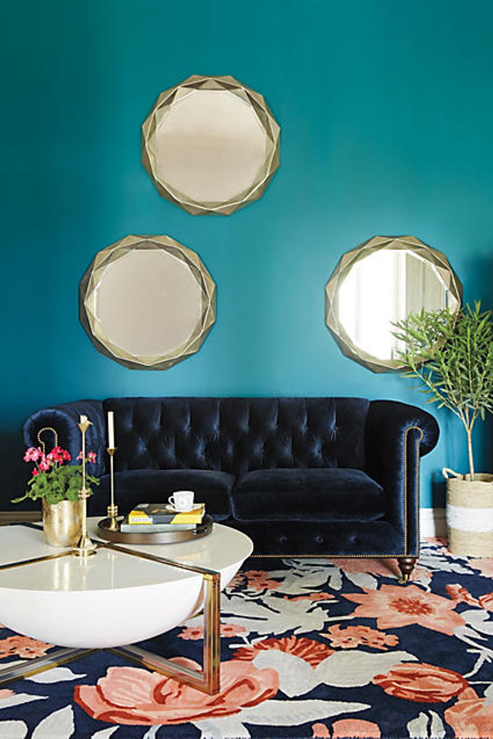 Jewel-tone teal living room with black velvet sofa and botanical floral area rug
