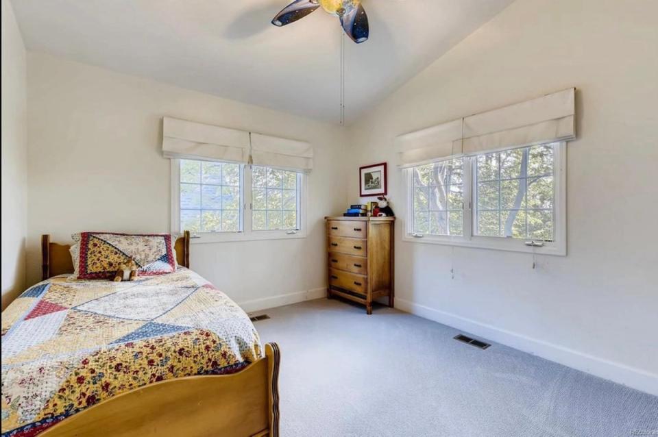 Serene bedroom with warm wood furniture, patterned bedding, bright windows, and restful neutral tones