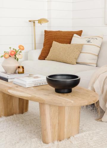 Coastal bedside styling with light wood table, black ceramic bowl, and warm earth tones