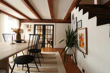 Modern rustic dining area with dark beams, white walls, black accents, and natural wood tones