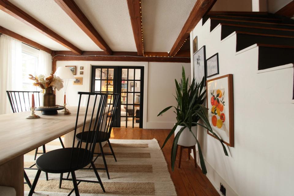 Modern rustic dining area with dark beams, white walls, black accents, and natural wood tones