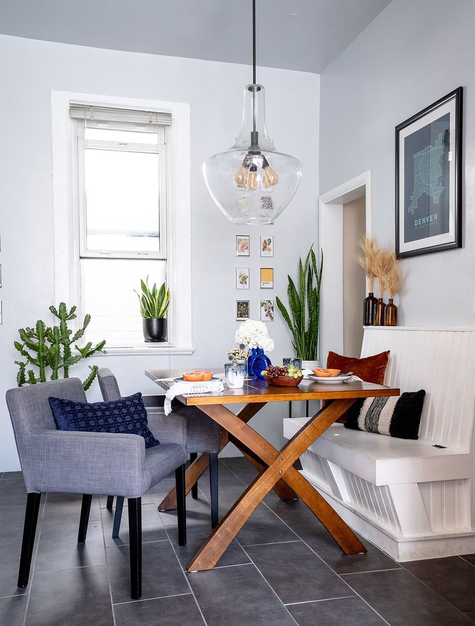 Cozy compact dining nook with modern x-base wood table, navy accents, potted plants, and bright natural light