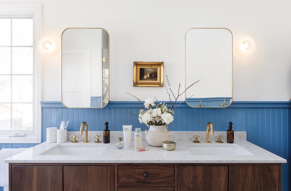 Nautical bathroom with blue shiplap wainscoting and brass sconces