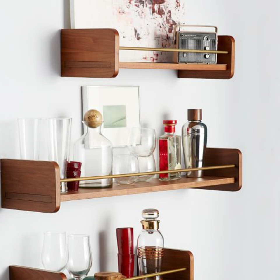 Mid-century modern walnut shelves displaying glassware and barware against clean white walls