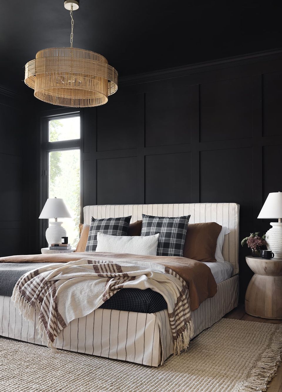Dark contemporary bedroom with black walls, woven pendant light, pinstriped upholstered bed, and warm brown accents for dramatic elegance