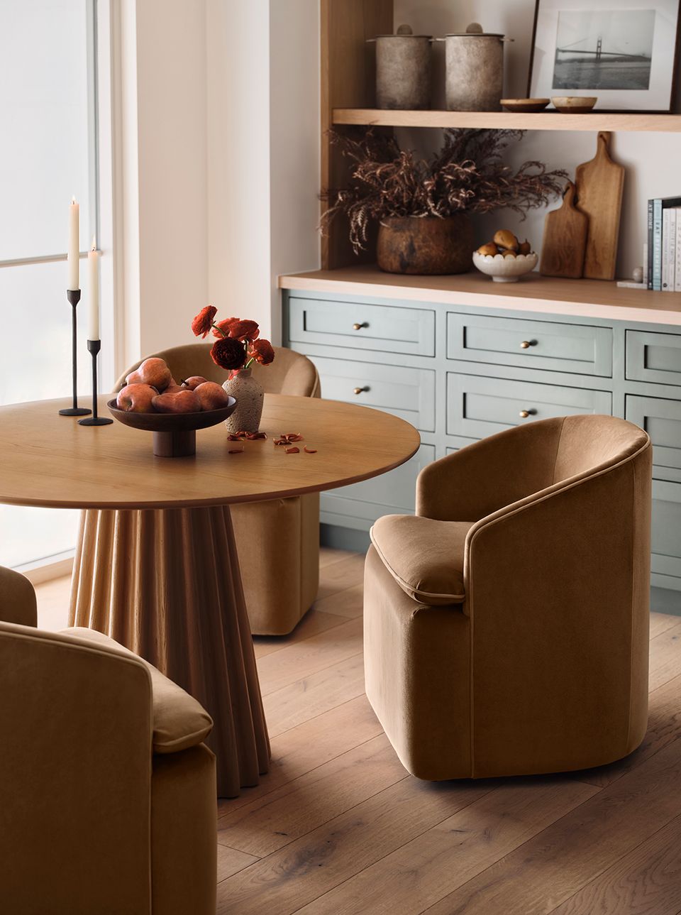 Warm contemporary round dining with caramel leather chairs and light blue built-in cabinetry backdrop