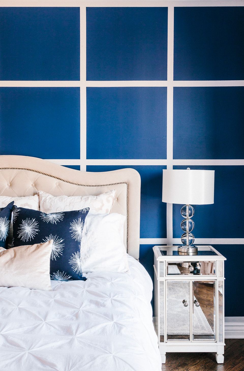 Contemporary geometric bedroom with bold navy grid accent wall and crisp white bedding