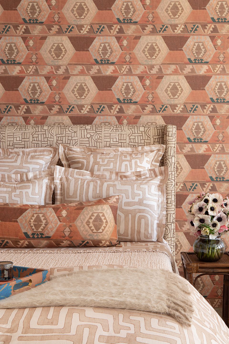 Eclectic boho with rust terracotta geometric wallpaper, layered patterned pillows, and warm tones