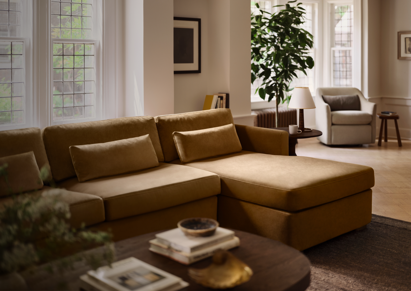 Gold velvet sectional sofa with chaise in a bright, plant-filled living room
