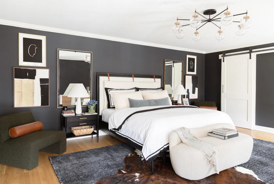 Dark gray contemporary bedroom with cream bedding, modern brass lighting, and curated wall art