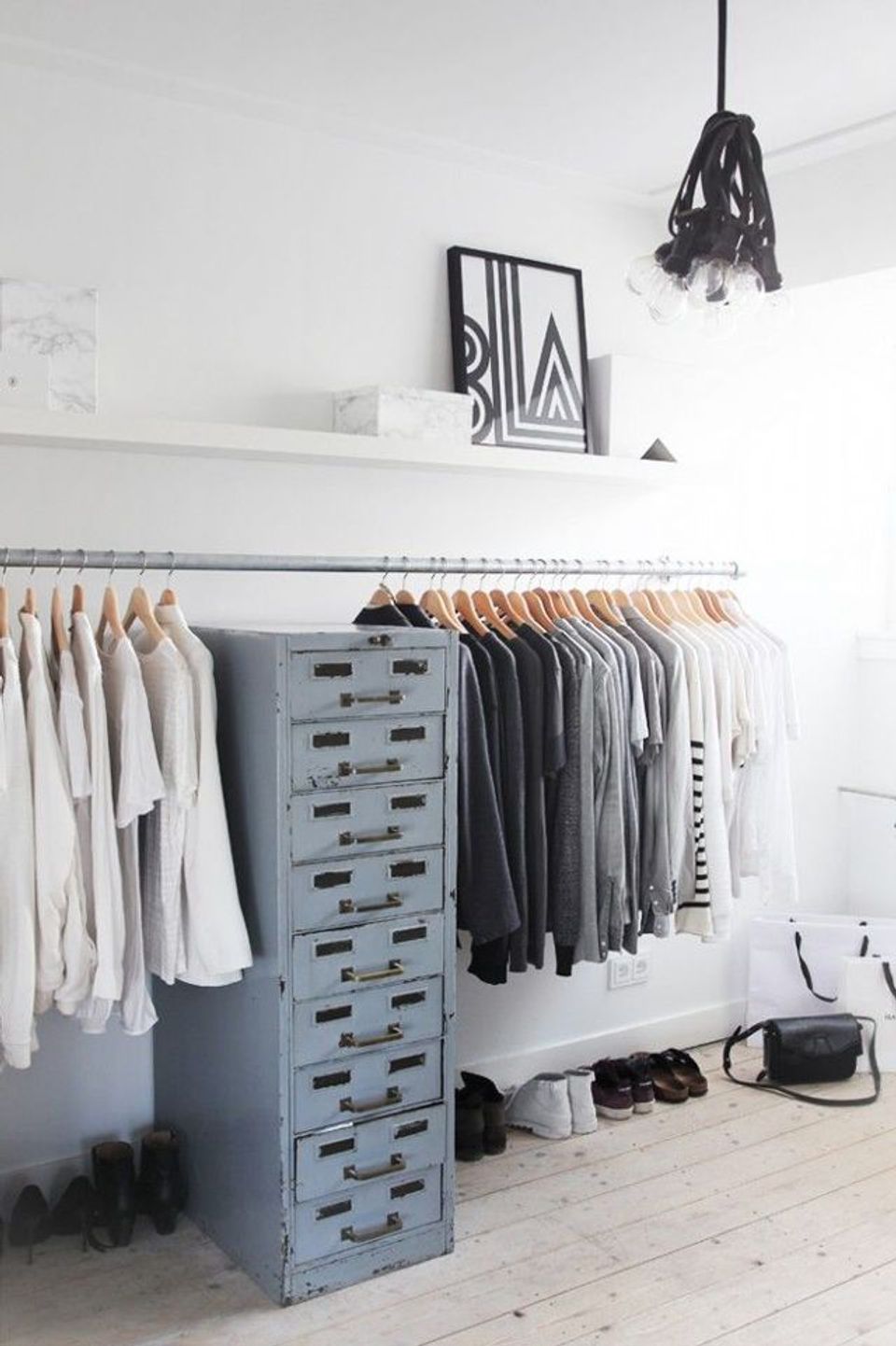 Minimalist walk-in closet with monochrome palette, organized clothing rails, and industrial blue storage drawers