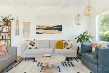 Bright living room with light gray sectional, woven accents, plants, and warm contemporary design