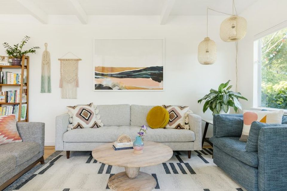 Bright living room with light gray sectional, woven accents, plants, and warm contemporary design
