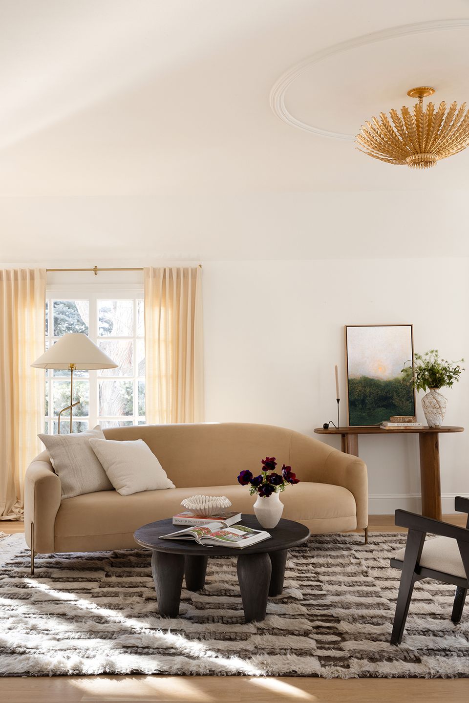 Modern minimalist living room in cream and beige with curved sofa, sculptural brass light, and natural textures