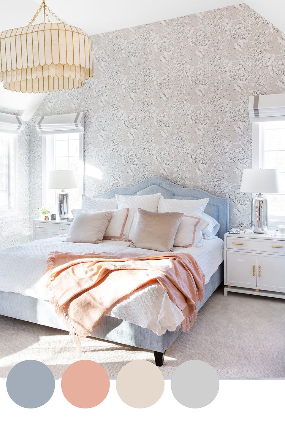 Serene coastal bedroom with soft blue, blush, and cream palette. Delicate patterned wallpaper, brass pendant, and layered textures create a tranquil, sophisticated retreat.