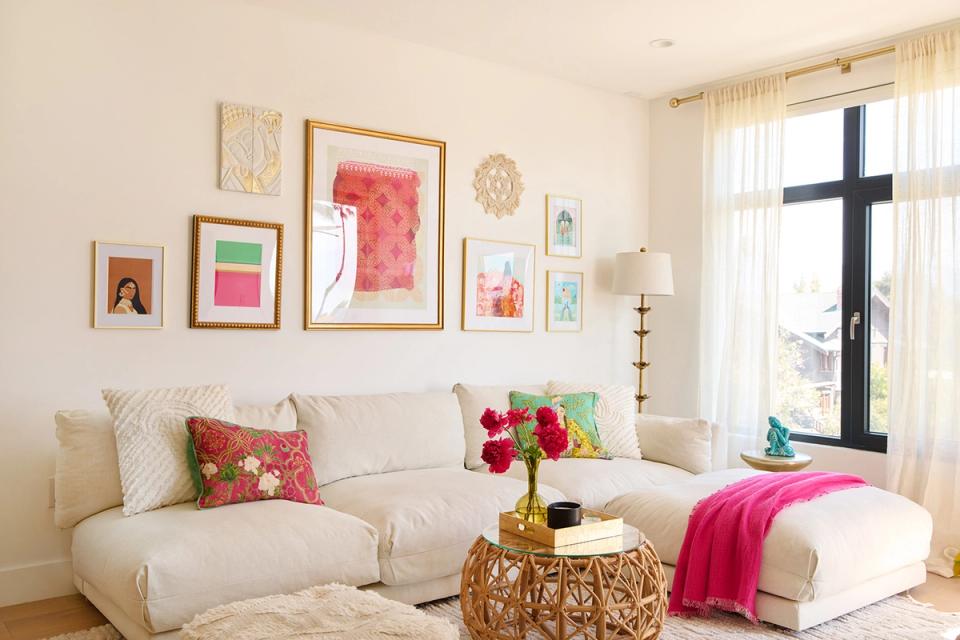 Airy boho living room with cream curved sofa, colorful gallery wall, and pops of magenta against soft neutrals.