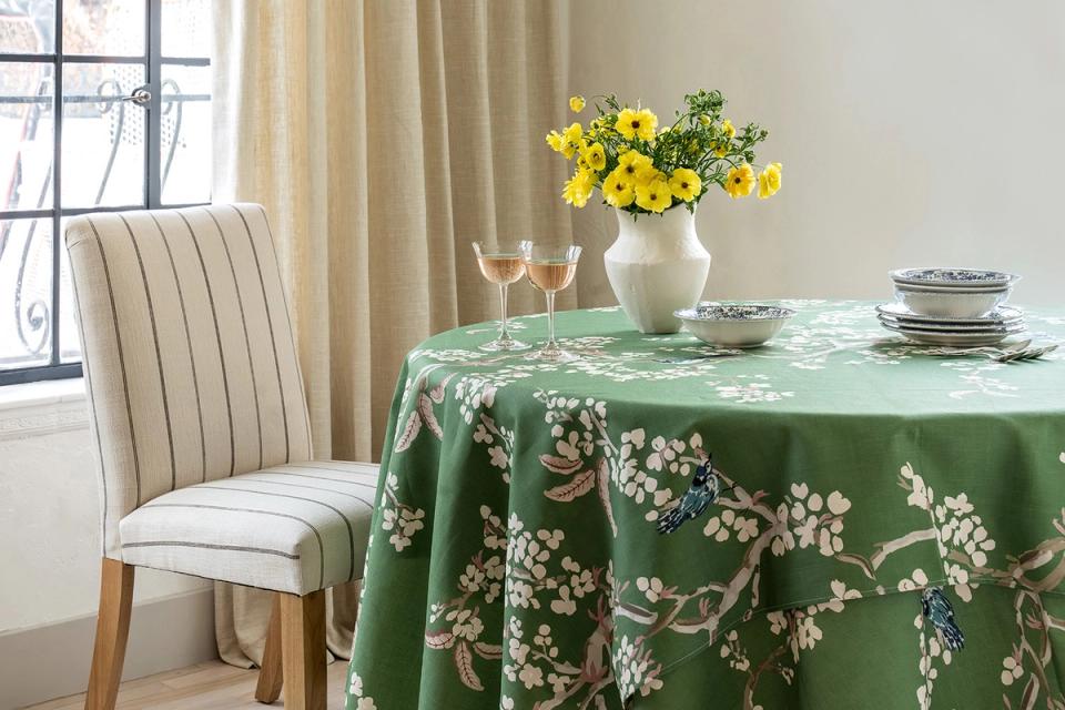 Classic botanical table setting with emerald floral tablecloth and cream striped dining chair