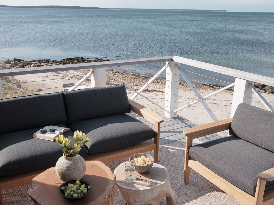 Luxury beachfront seating with curved black sofas, nautical white railings, and serene turquoise ocean views.