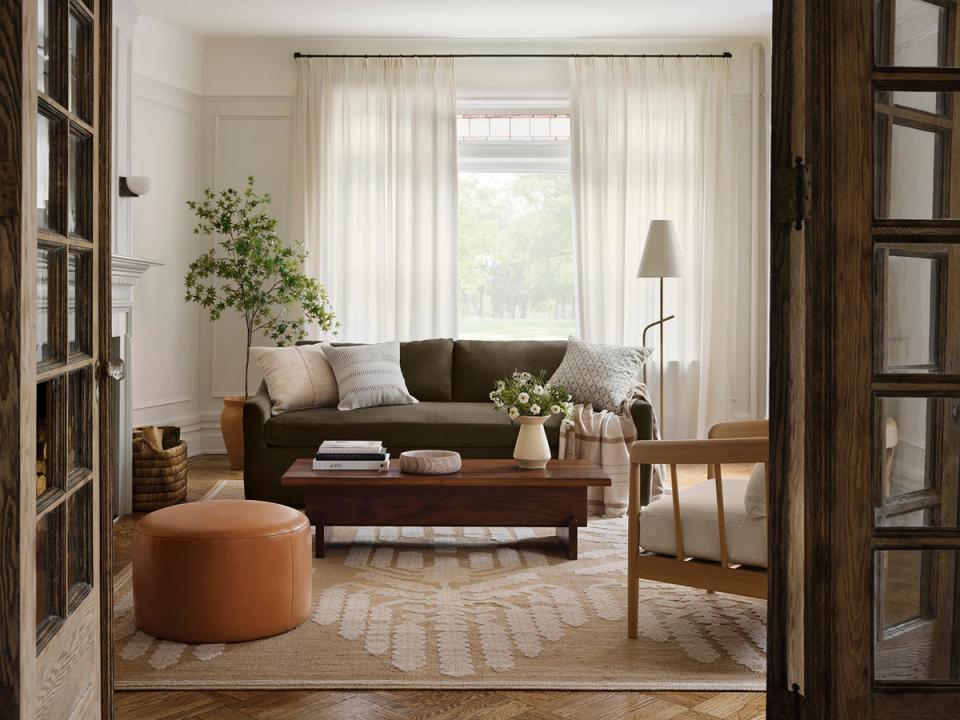 Eclectic boho lounge with olive green sofa, warm wood coffee table, layered textiles, and natural light.