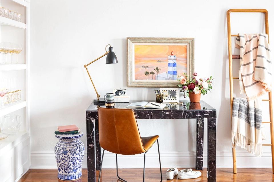 Mid-century modern office blending warm cognac leather chair, black industrial desk, brass lamp, and natural wood elements in refined neutral tones