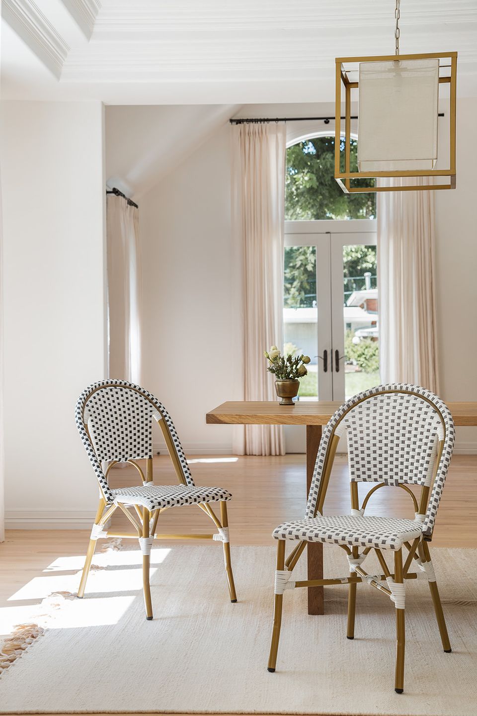 Bright Parisian-style dining nook with checkered chairs, natural wood table, and soft cream drapery