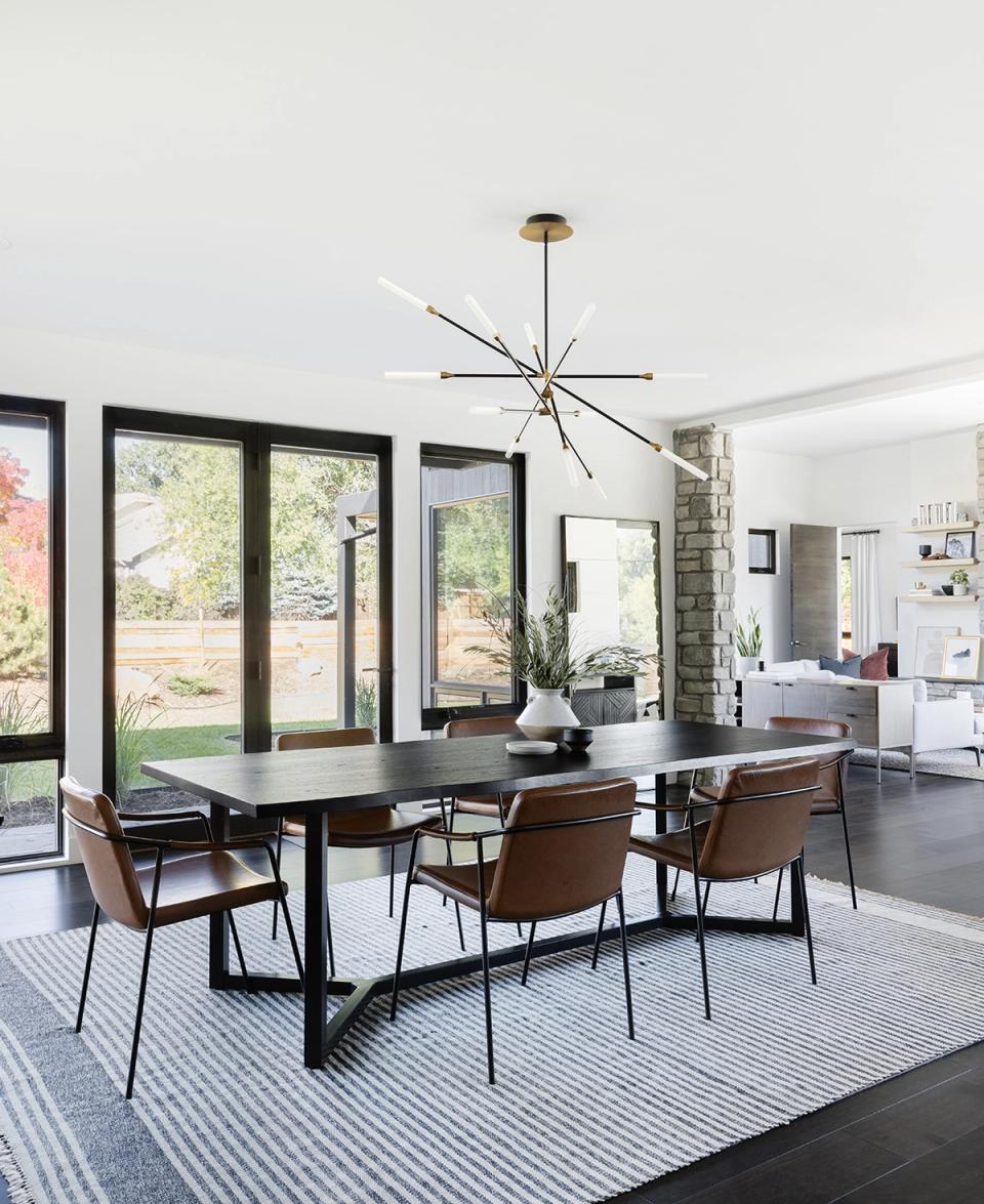 Modern dining space with black table, mid-century chairs, geometric pendant light, and bright natural wood tones