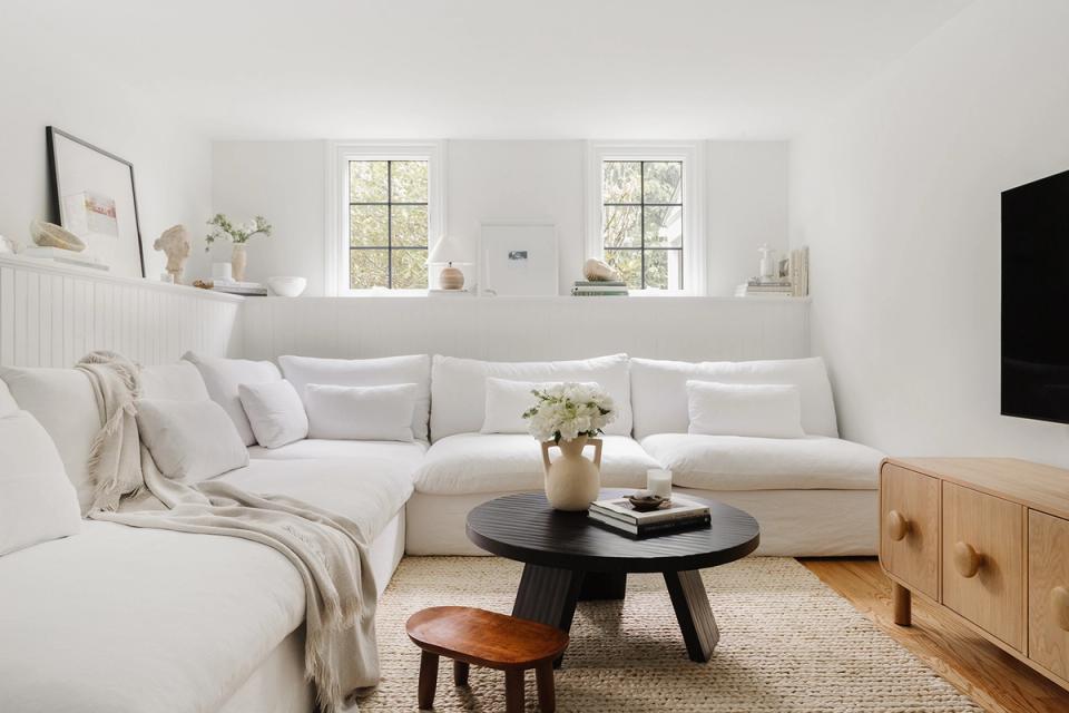 Minimalist Scandinavian living room with cream sectional, natural wood accents, and soft neutral palette