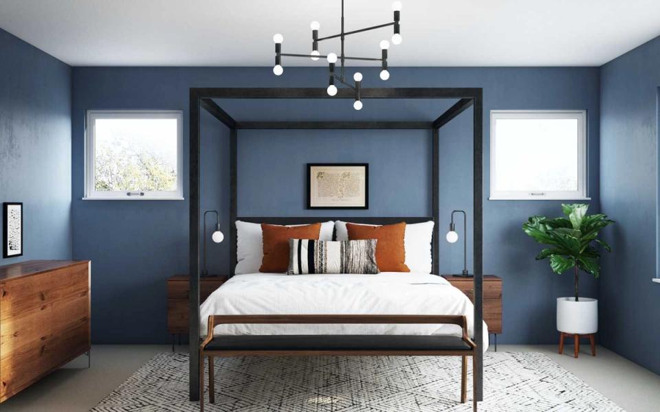 Industrial bedroom with muted blue walls, metal canopy frame, warm wood accents, and pendant lighting creating a modern yet inviting atmosphere.