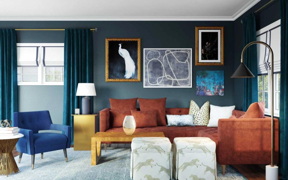 Eclectic living room with deep teal walls, rust-orange sofa, blue velvet chair, and gold-framed gallery wall creating a cohesive jewel-tone aesthetic.