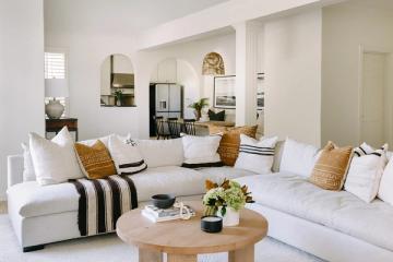 Modern minimalist lounge featuring white sectional, gold accents, and black striped details