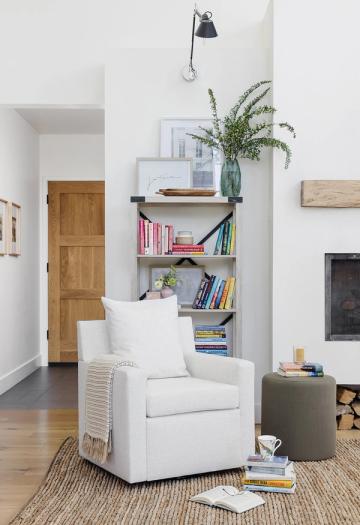 Scandinavian reading nook with white armchair, open shelving, natural wood accents, and soft neutral palette