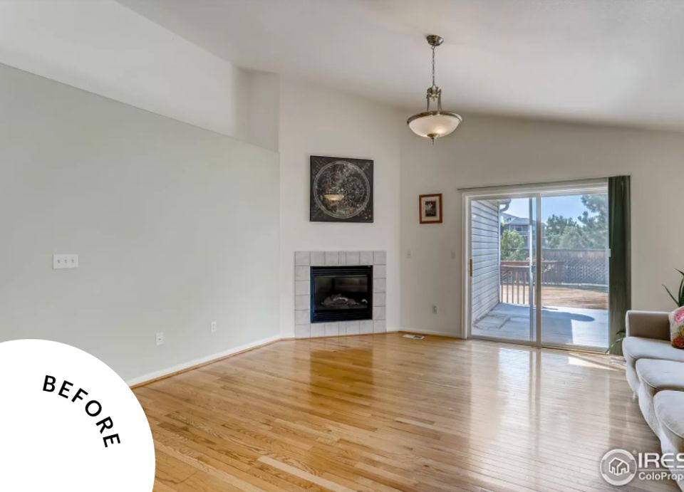 Spacious open-concept room with honey wood floors, fireplace, and bright natural light—before transformation