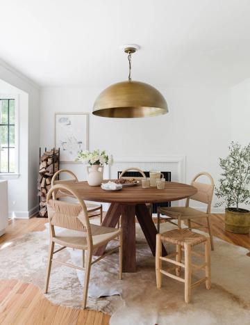 Modern farmhouse dining space with round wood table, natural chairs, and brass dome pendant