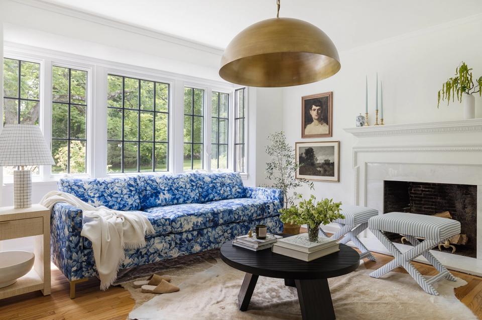 Bright living room with blue patterned sofa, brass pendant, and fireplace.