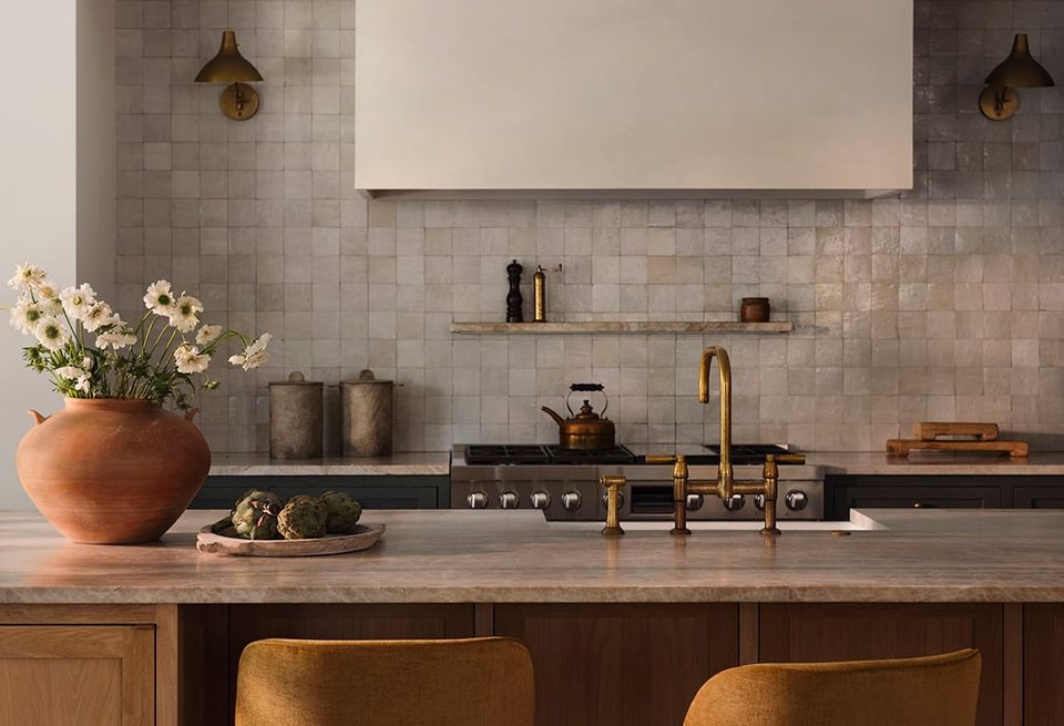 Warm contemporary kitchen with gray subway tile, warm wood cabinetry, brass fixtures, and terracotta accents