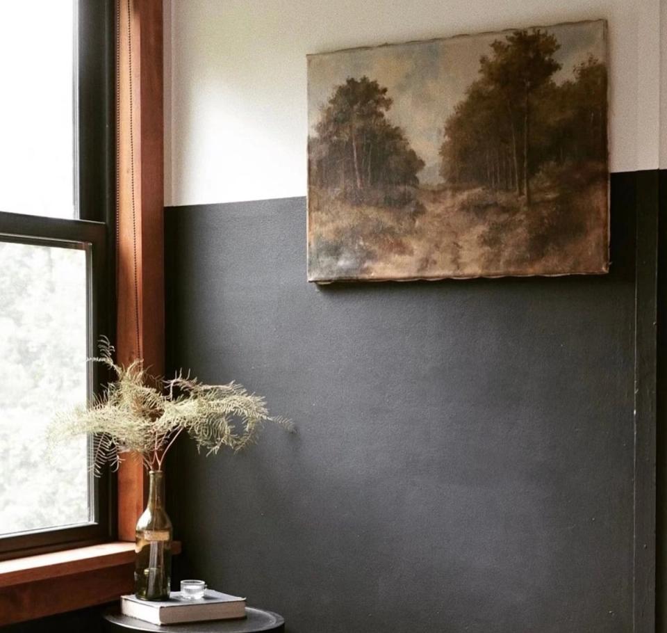 Contemporary entryway with slate gray color-block walls, wood-frame window, vintage landscape artwork, and botanical accent creating refined, grounded mood