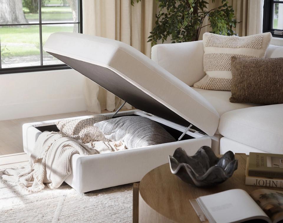 Contemporary cream sectional with storage ottoman and natural wood accents near large windows