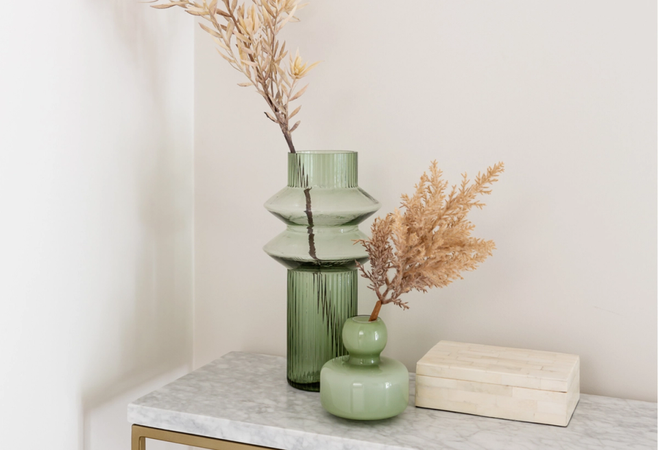 Minimalist dried flower styling with sage glass vessels and natural wood accent table