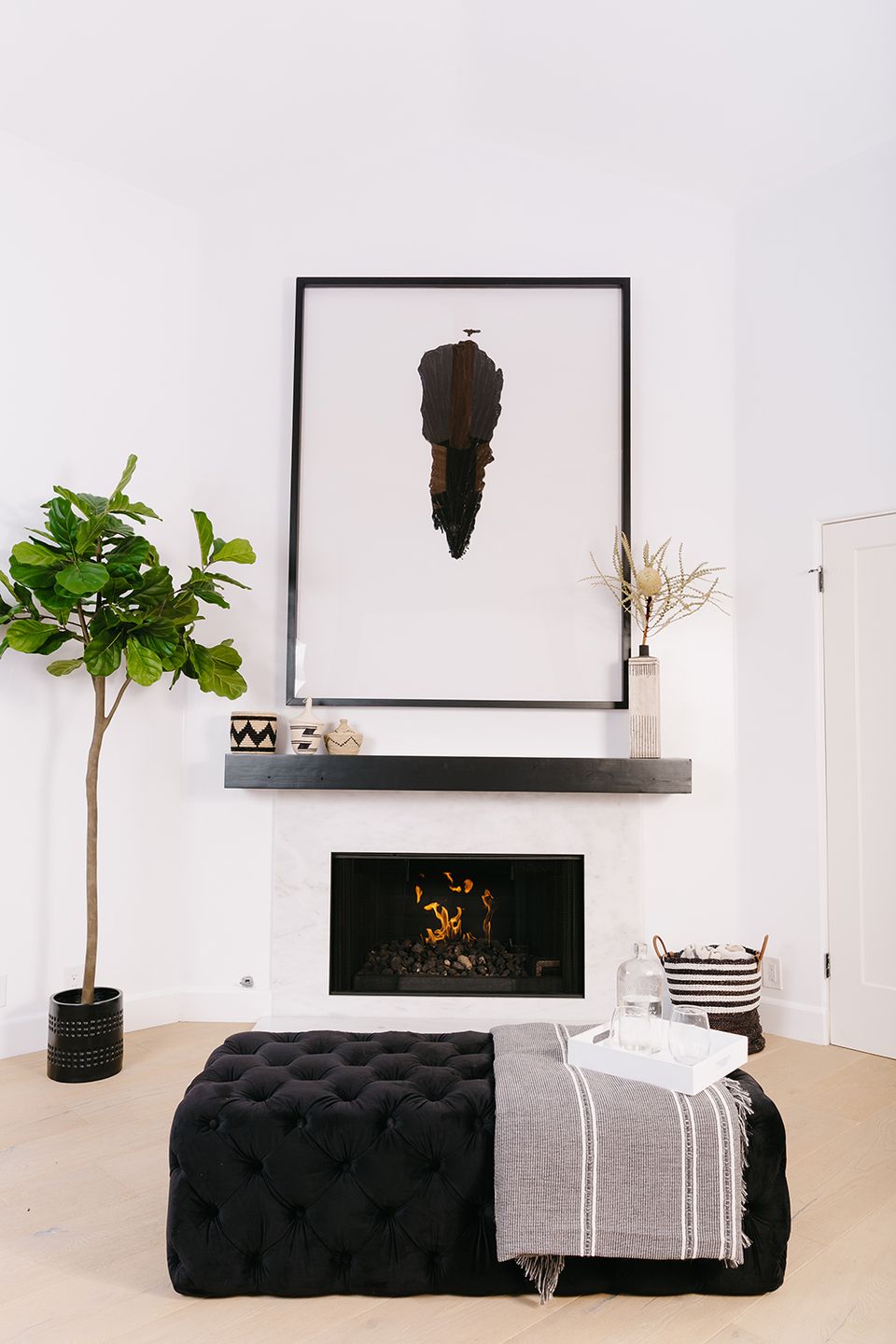 Minimalist fireplace nook with crisp white walls, black frame artwork, and monochromatic styling