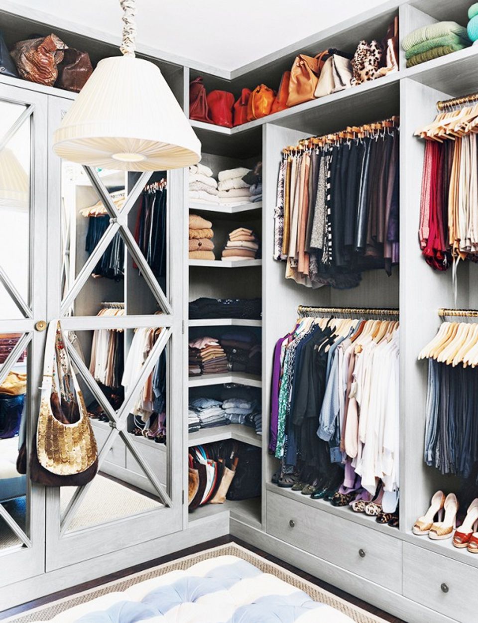 Bright farmhouse closet with white cabinetry, organized shelving, and color-coordinated clothing displays