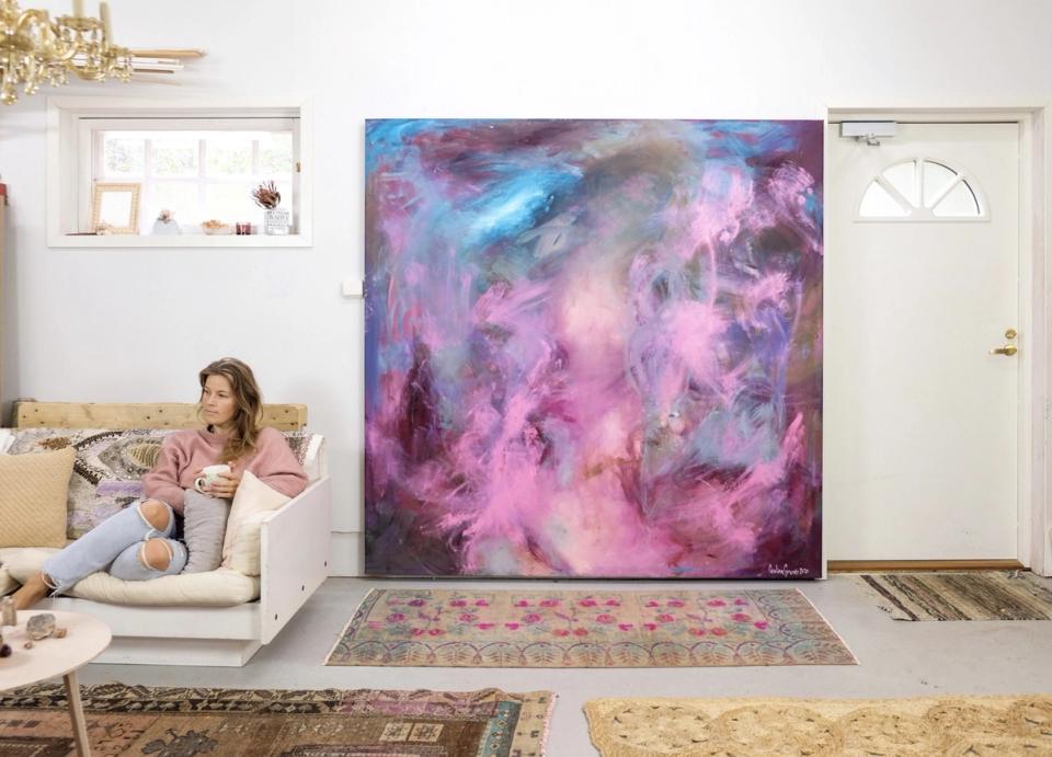 Bright artist studio with cream sofa, large abstract painting in purple and blue tones, minimalist Scandinavian aesthetic