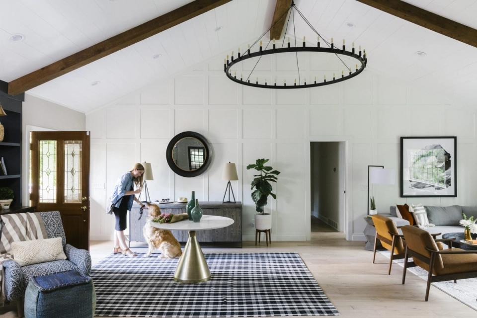 Bright farmhouse living room with exposed beams, gingham rug, vintage pendant light, and warm wood accents creating rustic comfort