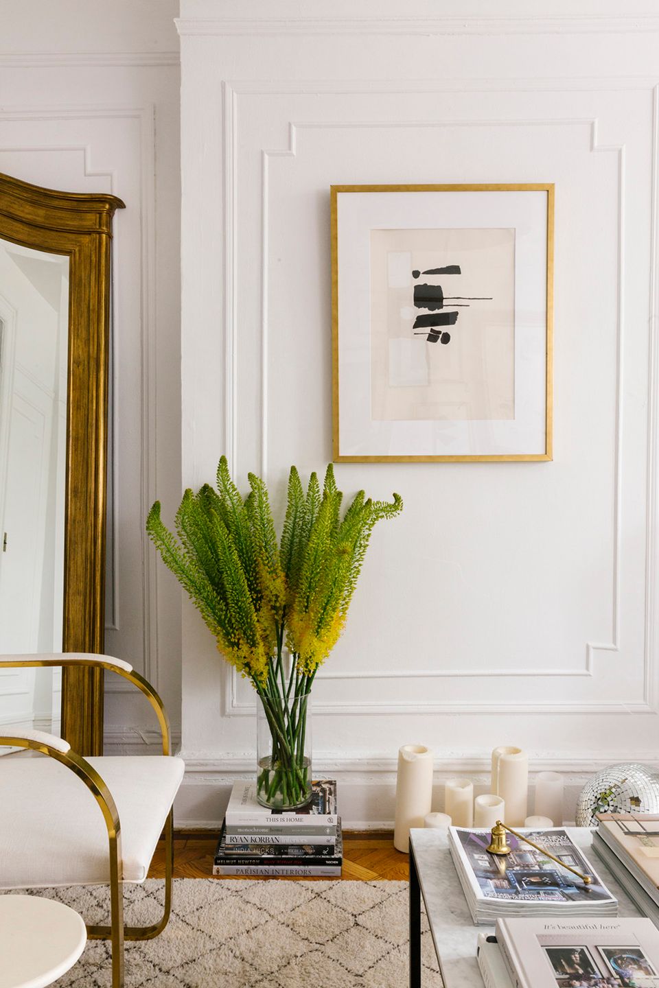 Sophisticated space with raised panel moulding, gold accents, greenery, and refined gallery aesthetic