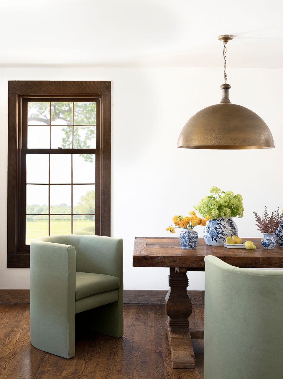 Contemporary dining with sage upholstered chair, brass pendant, and eclectic vintage-inspired wood table